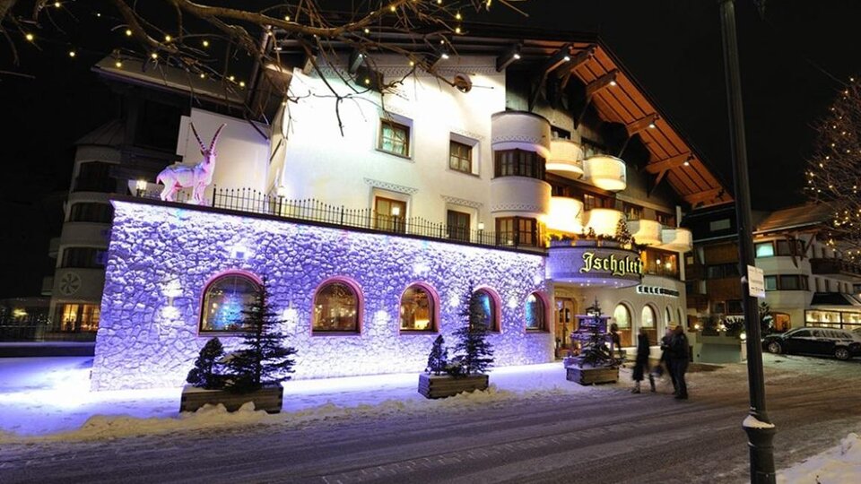 A charming hotel in a snowy town at night. The facade is illuminated with colorful lights, creating a festive atmosphere.