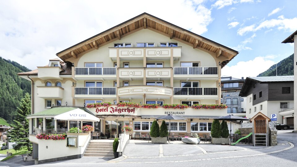 Ein charmantes Hotel mit alpenländischem Design und mehreren Balkonen. Umgeben von Bergen und einer ruhigen Umgebung.