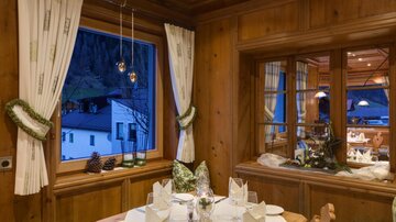 Ein gemütlicher Essbereich mit Holzverkleidung und traditionellem Design. Der Tisch ist gedeckt und das Licht schafft eine einladende Atmosphäre.