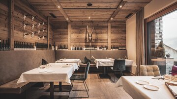 A modern restaurant with wooden walls and elegant tables. The atmosphere is cozy and inviting with large windows that let in light.