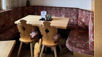 A cozy restaurant with wood decor and a TV corner showing a sports game. At the table are decorative chairs, and the ambiance is inviting.