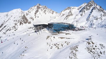 A modern building in snow-covered mountains. Skiers are enjoying the day in a beautiful winter landscape.