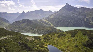 An impressive mountain landscape with green hills and clear lakes. The clouds in the sky give the scene a peaceful atmosphere.