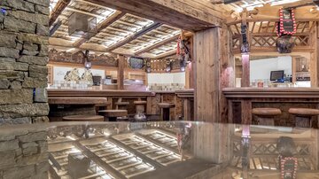 Ein gemütliches Restaurant mit holzgetäfeltem Interieur und einer einladenden Bar. Der Raum hat eine warme Atmosphäre und reflektiert das rustikale Design.