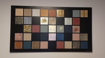 A collection of color sample panels on a black board. The panels display various textures and colors that can be used for design and decoration.