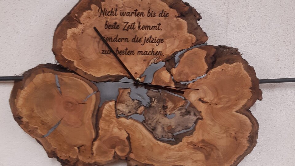 A decorative wall clock made of wood with a unique shape. It features the saying: "Do not wait for the best time to come, but make use of the present."