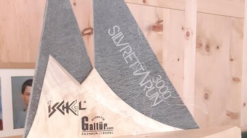 A decorative wooden sculpture in the shape of a sailboat with gray and light elements. The sculpture bears the inscription "Silvretta Run," suggesting an event or an award.