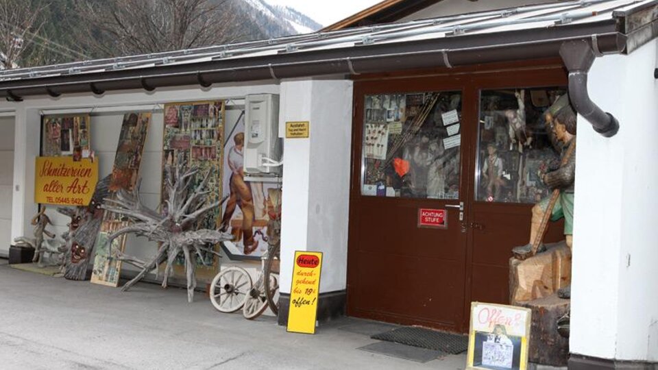 A traditional shop with wooden carvings and handicrafts. The facade displays various artworks and an inviting entrance door.