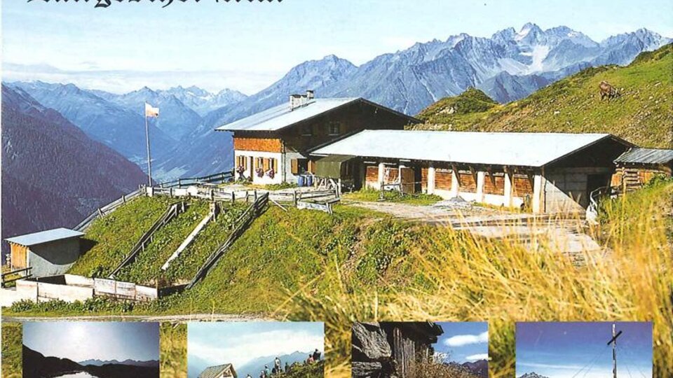 Eine malerische Alm umgeben von hohen Bergen und grünen Wiesen. Im Vordergrund ist das Gebäude der Langesthei Alm zu sehen.