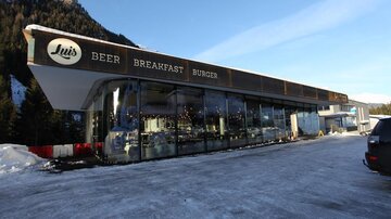 A modern restaurant with large windows in a wintery setting. The sign displays the offerings "Beer," "Breakfast," and "Burger."