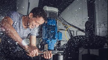 A man is working on a machine and is surrounded by water. He appears focused and engaged in his task.
