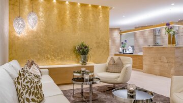 A modern living room with an elegant golden wall and stylish furniture. Soft lighting creates a cozy atmosphere.