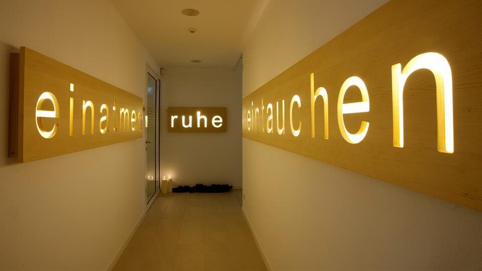 A bright hallway with stylish wooden signs. The words “breathe,” “calm,” and “exhale” gently glow, conveying a soothing atmosphere.