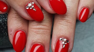 Rote Fingernägel mit glänzenden Akzenten. Die Nägel sind oval und gepflegt.
