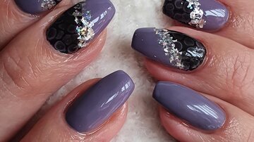 Schöne Fingernägel in lila und schwarz mit Glitzerakzenten. Die Nagelkunst ist elegant und trendig gestaltet.