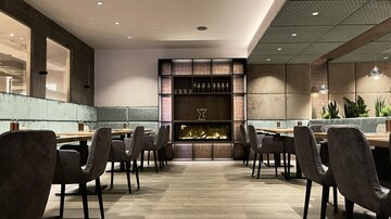 Ein elegantes Restaurant mit modernen Möbeln und sanfter Beleuchtung. Die Atmosphäre ist gemütlich und einladend.
