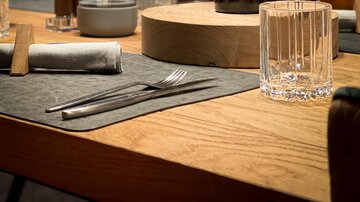 Ein stilvoller Tisch in einem Restaurant mit einer Flasche Wein und Gläsern. Die warmen Lichtverhältnisse schaffen eine gemütliche Atmosphäre.