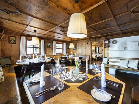 Ein gemütliches Restaurant mit Holzverkleidung und eleganten Tischen. Die warme Beleuchtung schafft eine einladende Atmosphäre.