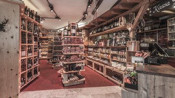 Ein gemütlicher Lebensmittelladen mit Holzregalen, die viele Produkte zeigen. Der Raum ist gut beleuchtet und lädt zum Stöbern ein.