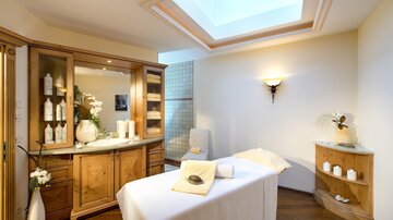 Ein entspannender Spa-Bereich mit einem Massagetisch und sanfter Beleuchtung. Der Raum ist hell und einladend, ideal für Wellness-Behandlungen.