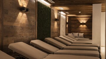 Ein entspannender Wellnessbereich mit eleganten Liegen und warmem Licht. Die Holzwände schaffen eine gemütliche Atmosphäre.
