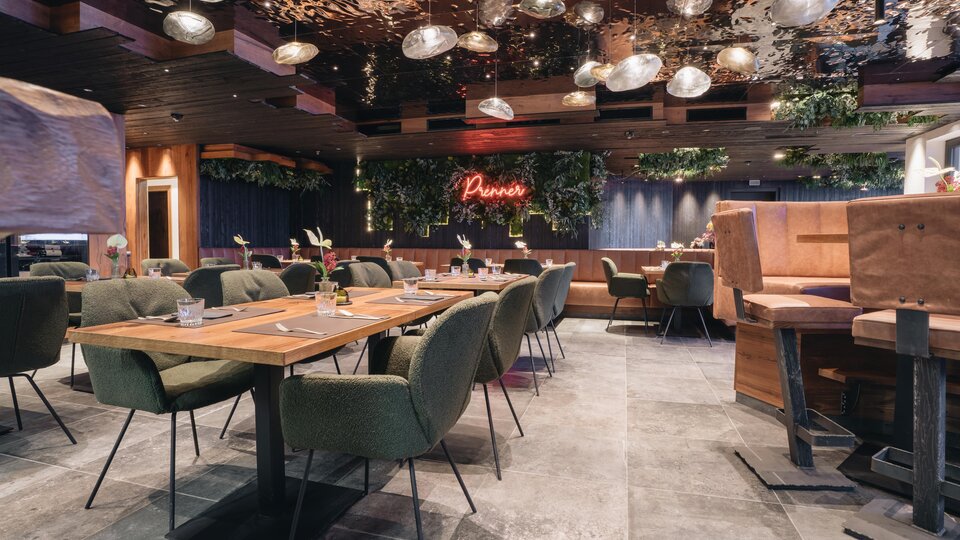 A modern restaurant with cozy tables and stylish chairs. The lighting and plants create an inviting atmosphere.