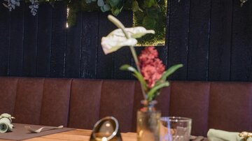 A stylish restaurant with a wooden sign and elegant dishes. In the background, a neon-colored inscription shines with the name "Prenner".