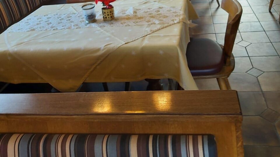 Ein einladendes Restaurant mit schön eingedeckten Tischen und Holzbank. Die Atmosphäre ist gemütlich und freundlich.