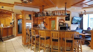 A cozy bar with wood paneling and stools. The atmosphere is welcoming and friendly.