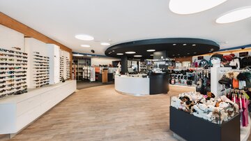A modern shop with a variety of sunglasses and accessories. The bright, inviting atmosphere is emphasized by the round ceiling lights.