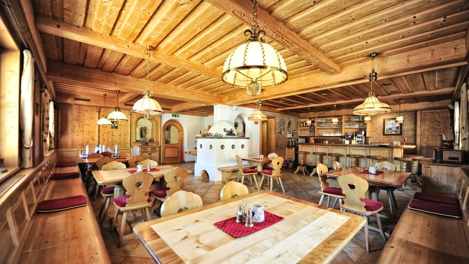 A cozy restaurant with wooden decor and warm lighting. The tables are neatly set and provide space for guests.