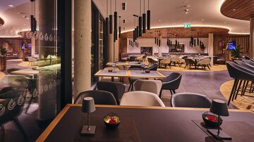 A modern restaurant with stylish furniture and soft lighting. The atmosphere is inviting and elegant.