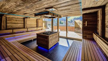 A modern wellness area with wooden paneling and comfortable seating. Large windows offer a view of the outside and provide plenty of natural light.