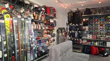 Ein gut sortierter Skisportladen mit verschiedenen Skiern, Helmen und Bekleidung. Im Hintergrund sind vielfältige Accessoires und Ausrüstungen für den Wintersport zu sehen.