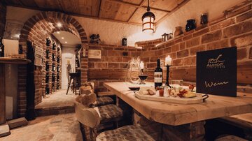 A cozy wine tavern with wooden tables and decadent food. The brick walls and soft lighting create an inviting atmosphere.