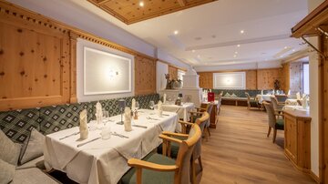 An elegant restaurant with wooden walls and a cozy atmosphere. The tables are nicely set and invite you to linger.