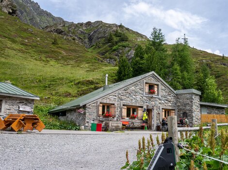 Ein gemütliches Steinhaus in einer malerischen Berglandschaft. Umgeben von grünen Wiesen und Bergen ist es ein idyllischer Rückzugsort.