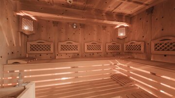 Eine finnische Sauna mit Holzverkleidung und gemütlicher Beleuchtung. Die Bänke sind aus hellem Holz und bieten Platz zum Entspannen.