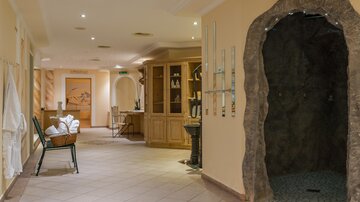A stylish spa area with soft lighting and a natural shower area. On the left, some towels and a relaxing chair can be seen.