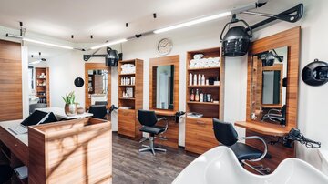 Ein moderner Friseursalon mit Holzregalen und Spiegeln. Es gibt mehrere Friseurstühle und eine Waschstation. | © Trofana Royal Resort/valentin_fotoo