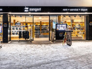 Ein Geschäft mit Sport- und Freizeitkleidung. Der Eingangsbereich ist einladend und die Umgebung ist schneebedeckt.
