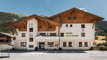 Ein charmantes Hotel mit traditioneller alpine Architektur und klaren Linien. Umgeben von Bergen und grünem Gelände bietet es eine einladende Atmosphäre.