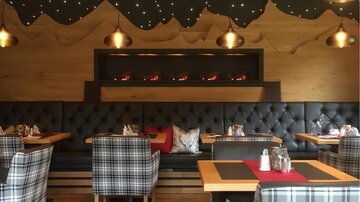 Ein stilvolles Restaurant mit gemütlichen, karierten Sitzplätzen und warmem Holzdekor. Die sanfte Beleuchtung schafft eine einladende Atmosphäre.