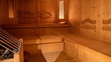 Eine gemütliche Sauna mit Holzverkleidungen und Sitzbänken. Das sanfte Licht schafft eine entspannende Atmosphäre.
