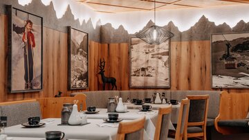 Ein gemütliches Restaurant mit Holzverkleidung und rustikalem Dekor. An den Wänden hängen Bilder und es gibt Tische, die für Gäste gedeckt sind.