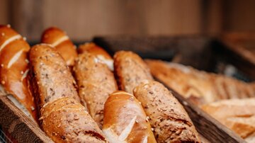 Ein Holzkorb mit frisch gebackenem Brot. Die Brote haben eine goldene Kruste und sind leckere, handwerklich zubereitete Backwaren.