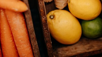 Kisten mit frischem Gemüse und Obst. Es sind Karotten, Ingwer, Zitronen und Limetten zu sehen.