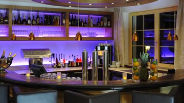 A modern bar with stylish lighting and a large selection of drinks. The counter is elegantly designed and provides an inviting atmosphere.