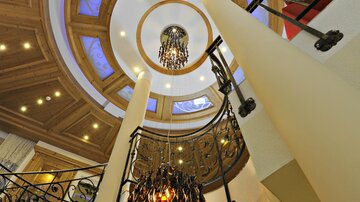 An elegant staircase with an artistic railing and an impressive ceiling light. The architecture conveys a sense of luxury and style.