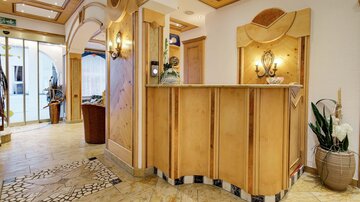 Ein eleganter Empfangsbereich mit Holzverkleidung und stilvollem Design. Der Raum ist hell und einladend, mit Pflanzen und einer gemütlichen Atmosphäre.